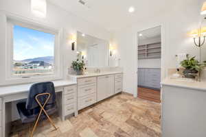 Bathroom with vanity, recessed lighting, a walk in closet, and light stone finish flooring