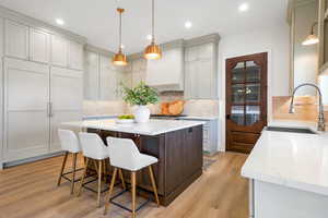 Kitchen featuring a breakfast bar, light stone countertops, decorative light fixtures, a center island, and dual tone cabinetry