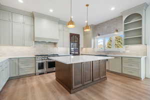 Kitchen featuring double oven range, decorative light fixtures, open shelves, a kitchen island, and backsplash