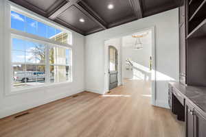 Unfurnished living room with light wood-type flooring, arched walkways, recessed lighting, beam ceiling, and coffered ceiling