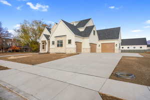 View of front of property featuring driveway, stone siding, roof with shingles, and stucco siding