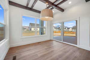 Unfurnished dining area featuring beamed ceiling, light wood finished floors, plenty of natural light, coffered ceiling, and a residential view