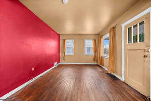 Unfurnished room featuring dark wood-type flooring and plenty of natural light