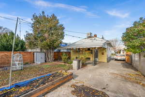 Back of house with a chimney, a garden, and a gate