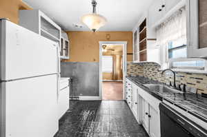 Kitchen with white cabinets, freestanding refrigerator, and healthy amount of natural light