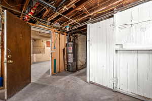Unfinished below grade area featuring gas water heater and wood walls