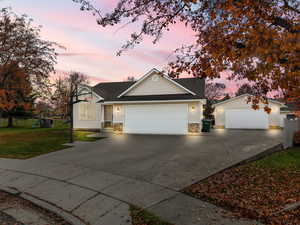 View of front of property featuring a playground, roof with shingles, a garage, stone siding, and concrete driveway
