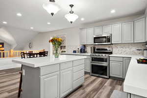 Kitchen featuring gray cabinets, stainless steel appliances, recessed lighting, backsplash, and a center island