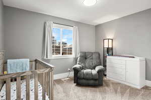 Carpeted bedroom featuring a nursery area and baseboards