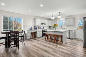 Kitchen featuring a breakfast bar, gray cabinetry, a center island, stainless steel appliances, and recessed lighting