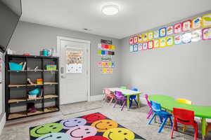 Recreation room featuring a textured ceiling and light carpet