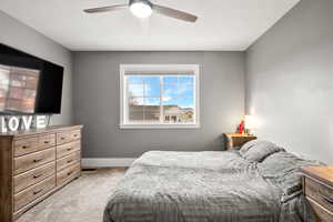 Bedroom with light carpet, ceiling fan, and a textured ceiling