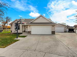 View of front of home featuring concrete driveway, stone siding, roof with shingles, and a garage