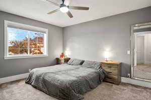 Bedroom with carpet flooring, a ceiling fan, and a textured ceiling