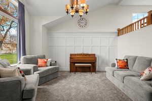 Sitting room featuring a decorative wall, a chandelier, carpet, and lofted ceiling
