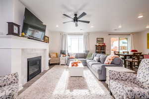 Living area featuring wood finished floors, healthy amount of natural light, a fireplace, recessed lighting, and ceiling fan