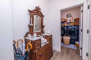 Bathroom featuring wood finished floors, vanity, and washer and dryer