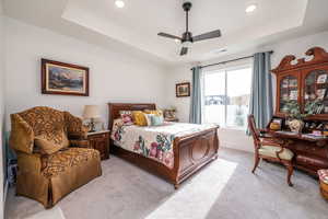 Primary Bedroom featuring a raised ceiling, light colored carpet, a ceiling fan, and recessed lighting