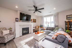 Living area with wood finished floors, a fireplace, recessed lighting, and a ceiling fan