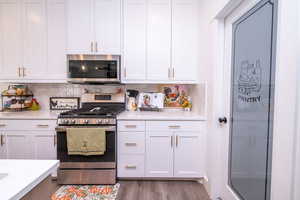 Kitchen featuring appliances with stainless steel finishes, white cabinets, and light stone counters