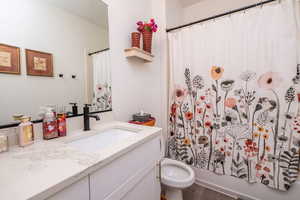 Full bathroom with vanity, shower / tub combo, and dark wood-style floors