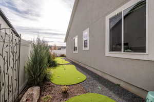 View of side of property with an area to practice putting, a fenced backyard, and stucco siding