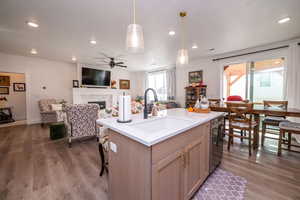 Kitchen with open floor plan, a kitchen breakfast bar, a fireplace, light stone countertops, and recessed lighting