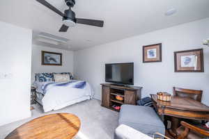 Carpeted bedroom featuring ceiling fan and attic access