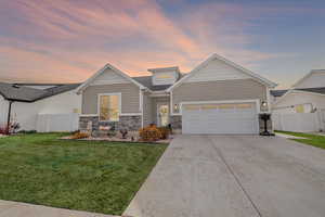 View of front facade with concrete driveway, stone siding, and an attached garage