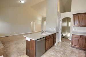 Kitchen with dishwasher, open floor plan, a peninsula, light countertops, and high vaulted ceiling