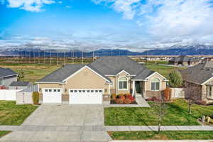 View of front of home with a mountain view, an attached garage, brick siding, driveway, and roof with shingles
