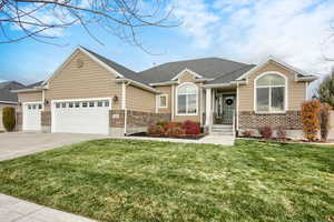 View of front of property featuring a front yard, driveway, and brick siding