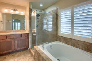 Full bath featuring vanity, a garden tub, a shower stall, and light tile patterned floors