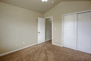 Unfurnished bedroom with lofted ceiling, carpet, and a closet