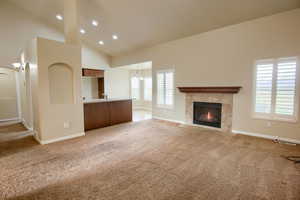 Unfurnished living room with light colored carpet, a tile fireplace, a chandelier, recessed lighting, and high vaulted ceiling