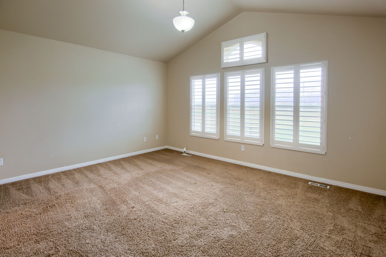 Empty room with carpet floors and high vaulted ceiling