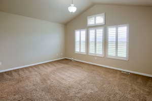 Empty room with carpet floors and high vaulted ceiling