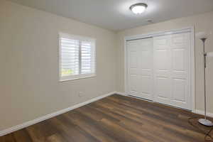 Unfurnished bedroom featuring dark wood-type flooring and a closet