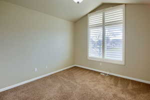 Carpeted spare room with lofted ceiling and baseboards