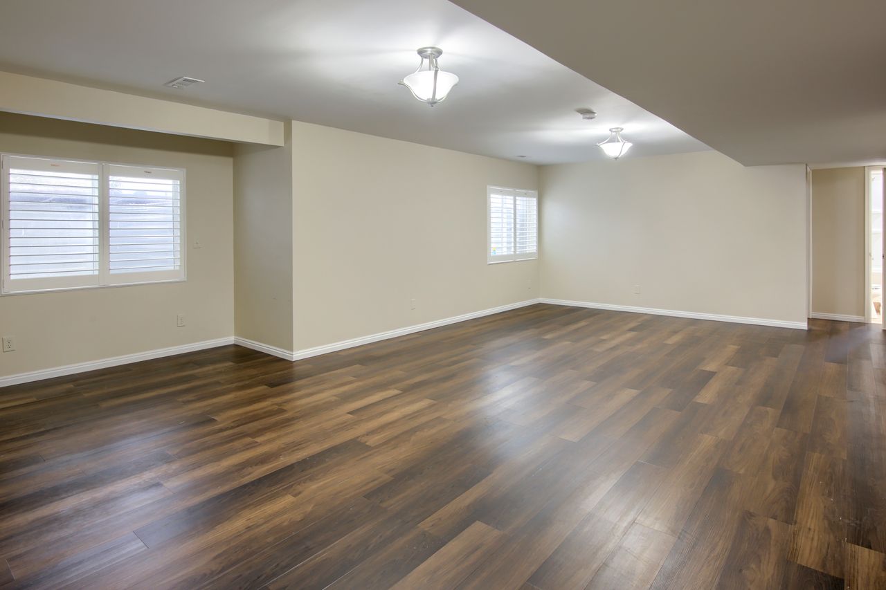 Spare room featuring dark wood-style flooring and baseboards
