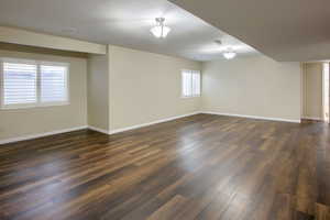 Spare room featuring dark wood-style flooring and baseboards
