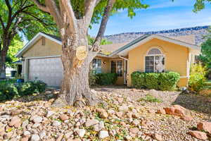 Ranch-style home featuring stucco siding, a mountain view, a garage, and roof with shingles