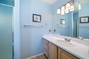 Bathroom featuring a shower stall, vanity, and dark tile patterned floors