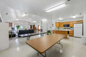 Dining room featuring light floors, lofted ceiling, and a textured ceiling