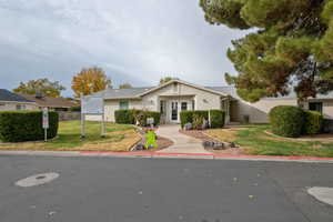 Ranch-style house featuring a front yard, stucco siding, and french doors