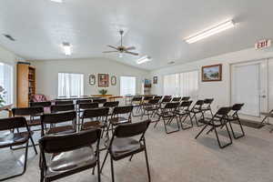Dining area featuring a textured ceiling, light colored carpet, plenty of natural light, ceiling fan, and lofted ceiling