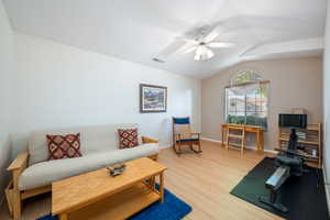 Living room featuring light wood-style floors, lofted ceiling, and a ceiling fan