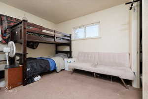 Carpeted bedroom with a barn door and a textured ceiling