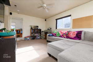 Carpeted living room with a ceiling fan