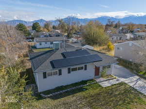 Back of property with a residential view, roof mounted solar panels, driveway, and a mountain view